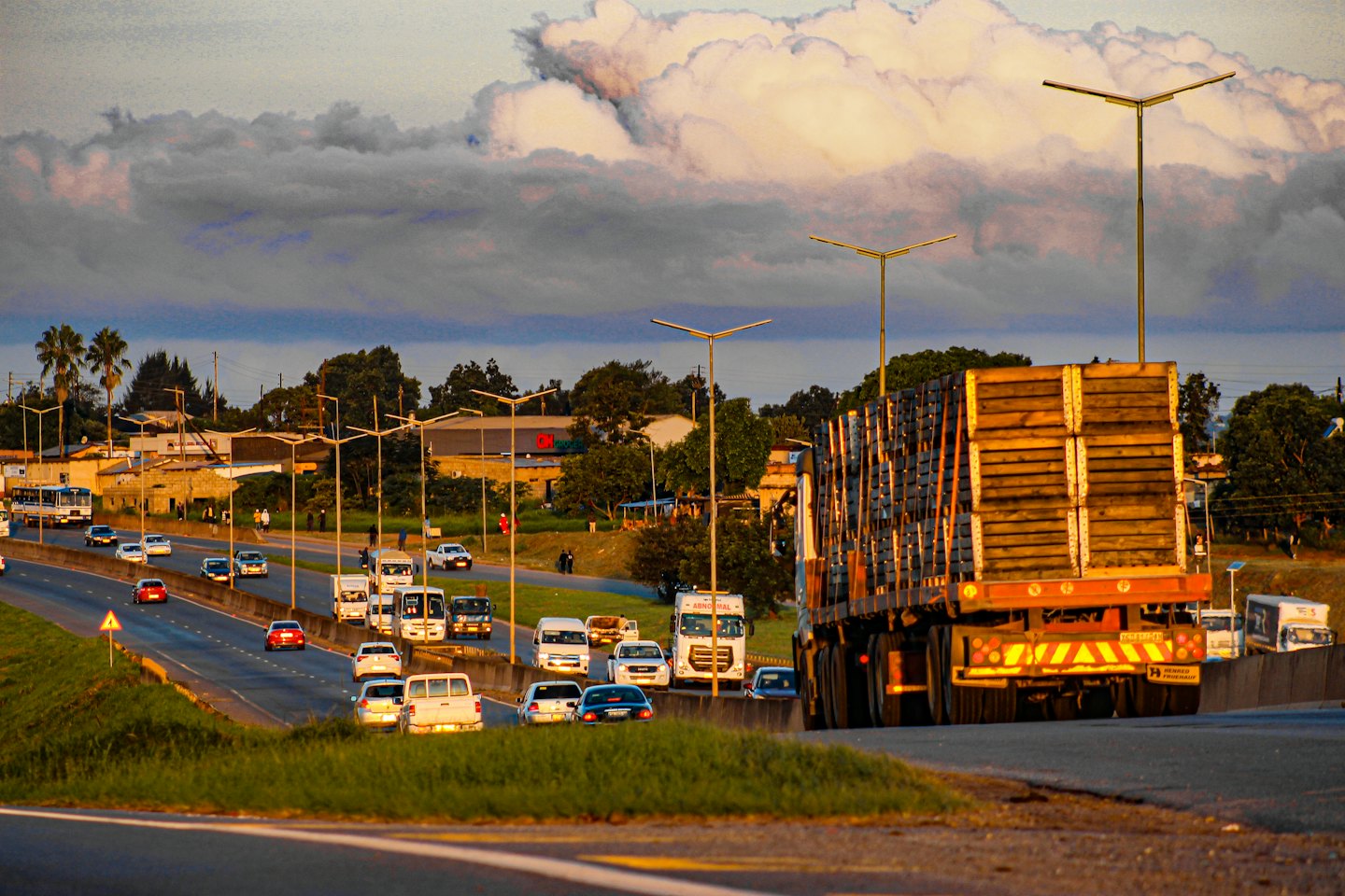 Cars and trucks on a highway at sunset with palm trees.
