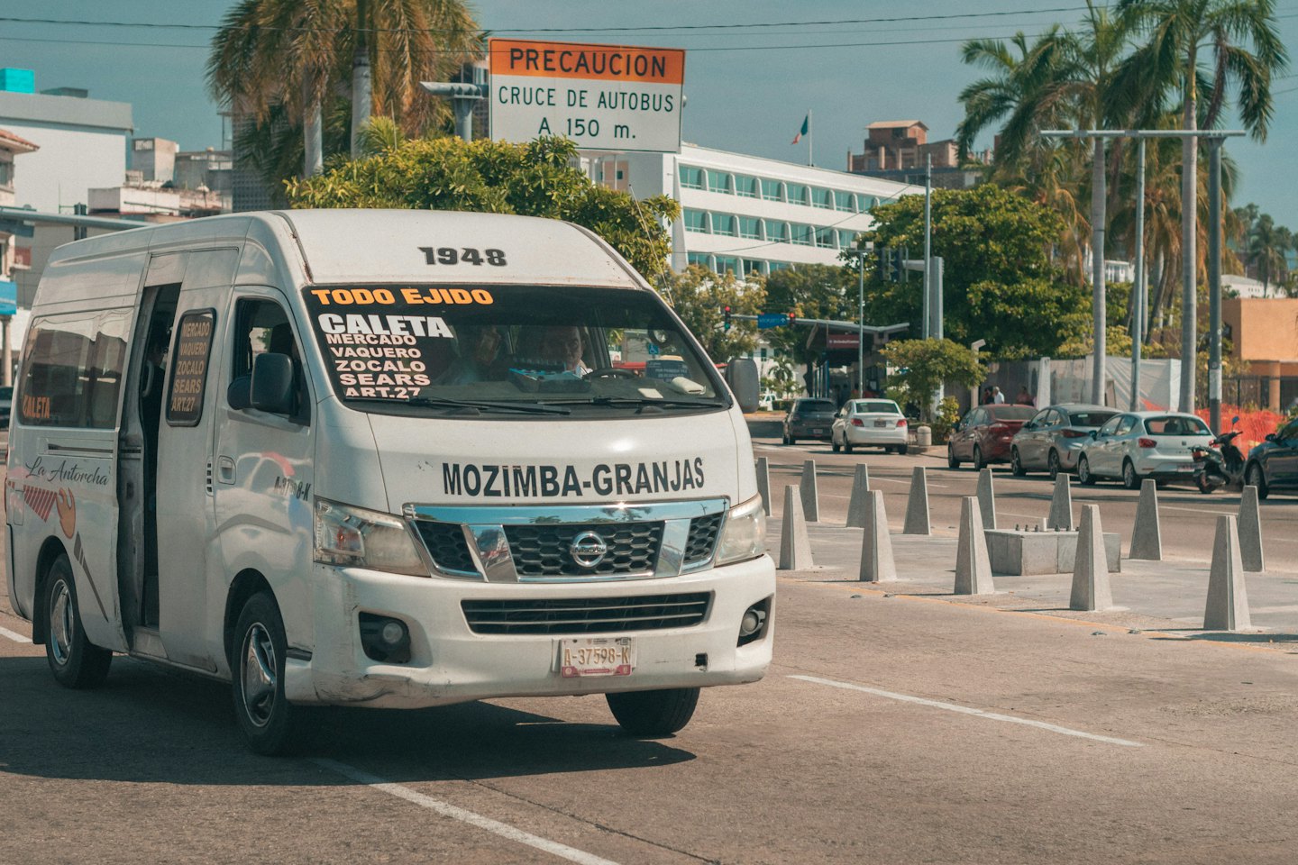 A passenger van with an open door driving down the street.