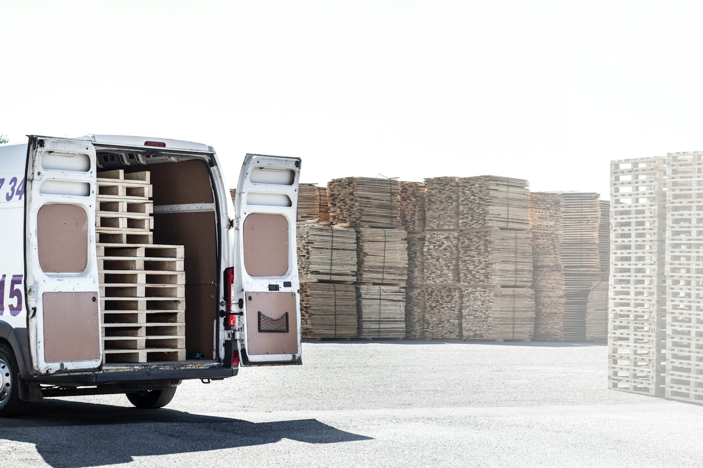 White cargo van with open doors loaded with wooden pallets.