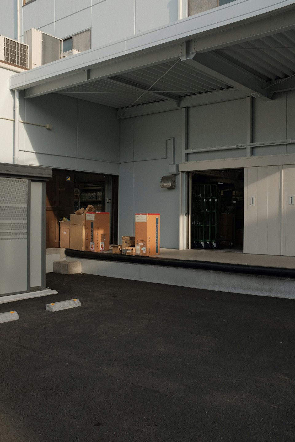 Cardboard boxes stacked outside a modern industrial loading dock.